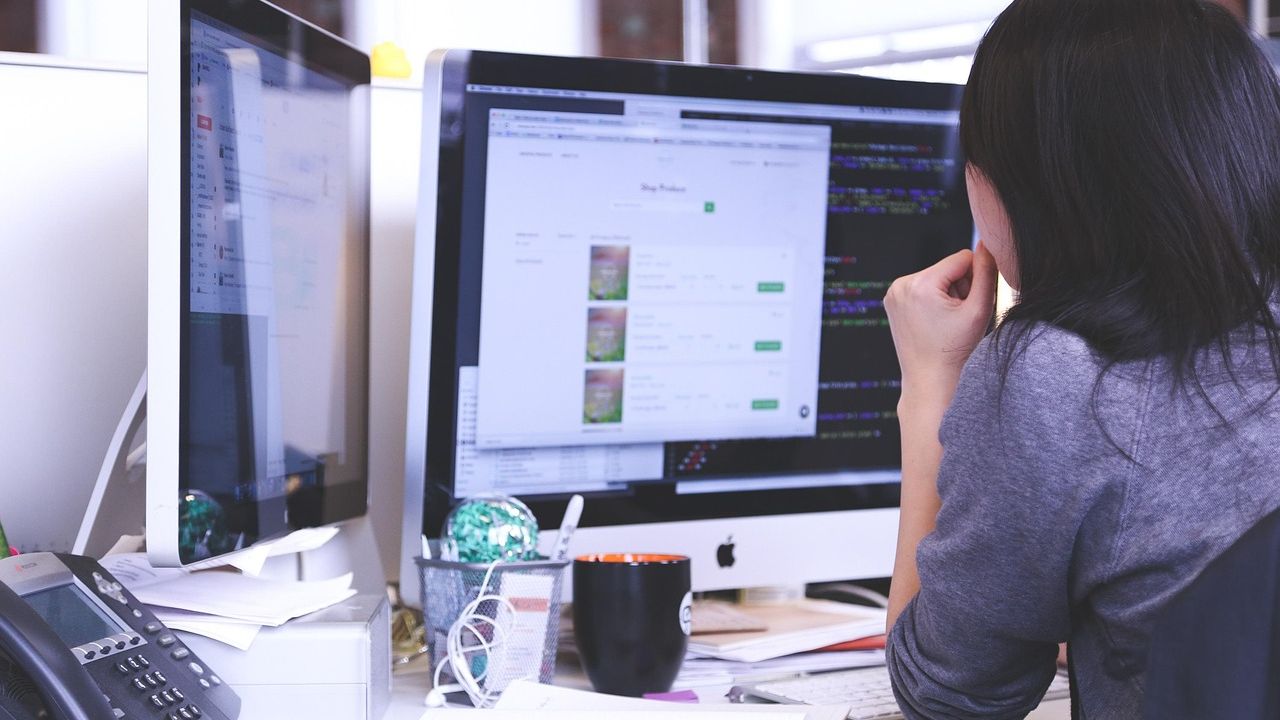 Photo of a person working at a desktop computer showing an online store page in a small office