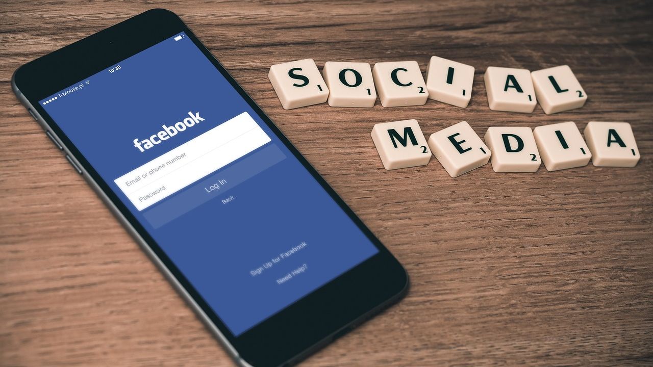 Photo of a phone showing a Facebook login screen beside letter tiles spelling SOCIAL MEDIA