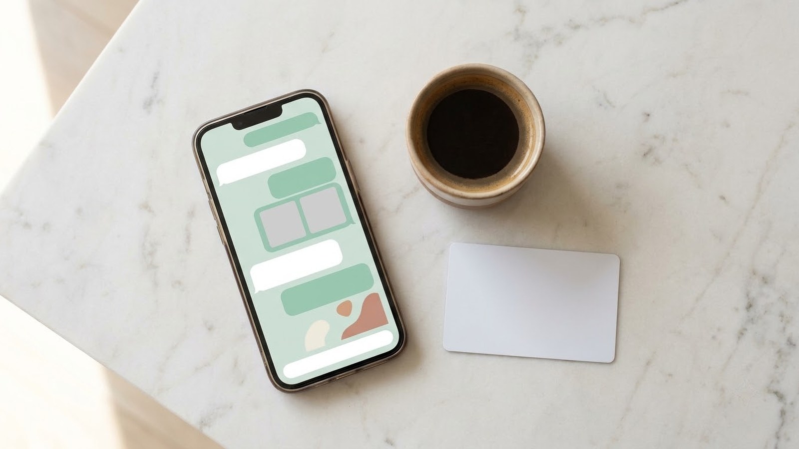 A phone on a stone surface showing a booking conversation, beside a coffee cup and a key card