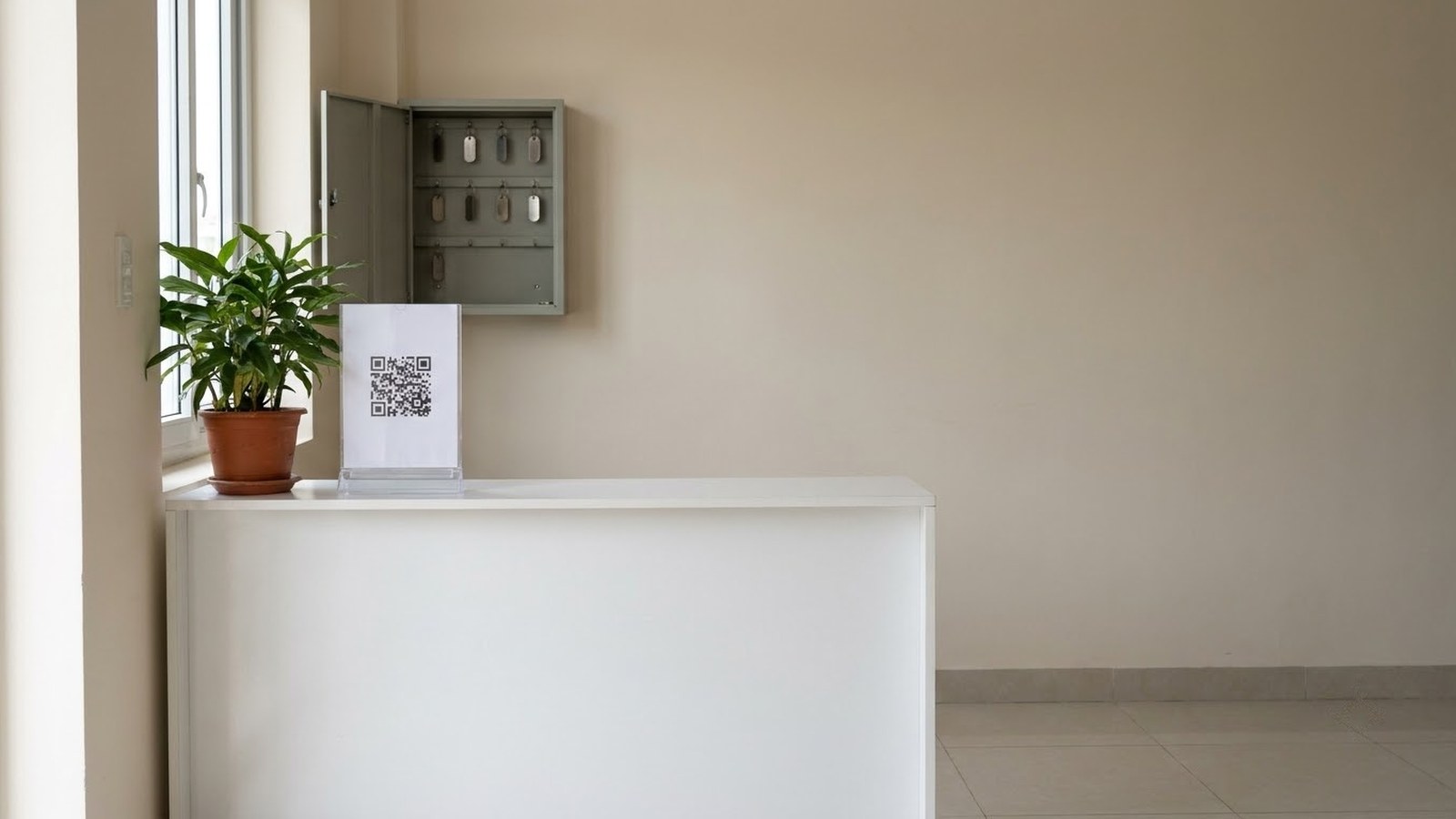 Góc lễ tân không có người trực, mã QR đặt trên quầy và tủ treo chìa khoá gắn trên tường